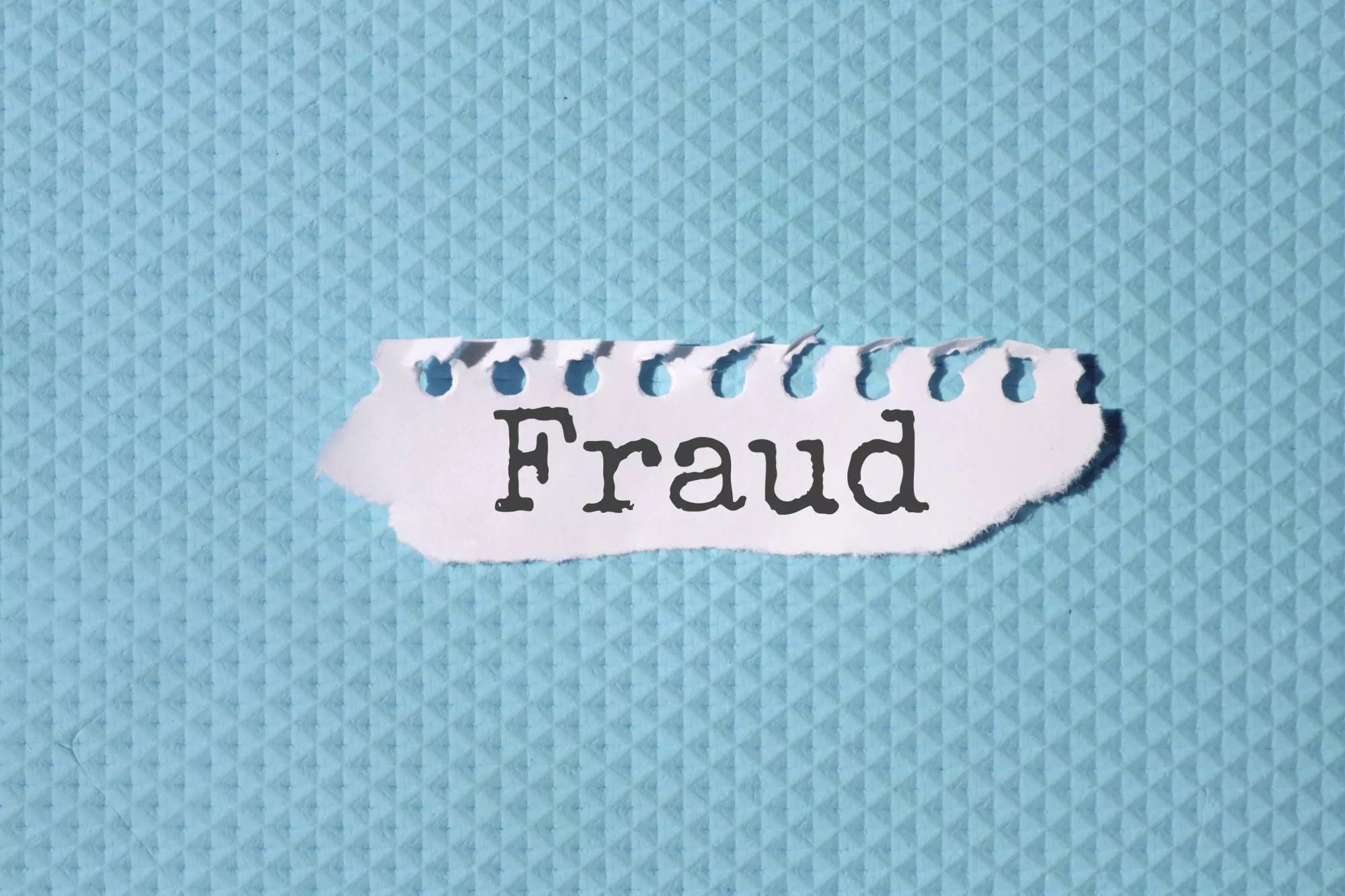 a torn paper on a blue background that has fraud on it to represent a fake check