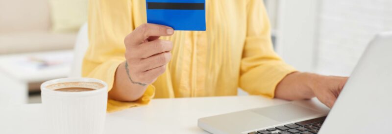 a woman holding a blue credit card and using a laptop to research what is paypal credit