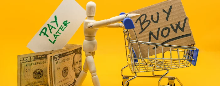 wooden doll of a person with shopping cart buying now with Klarna and paying later