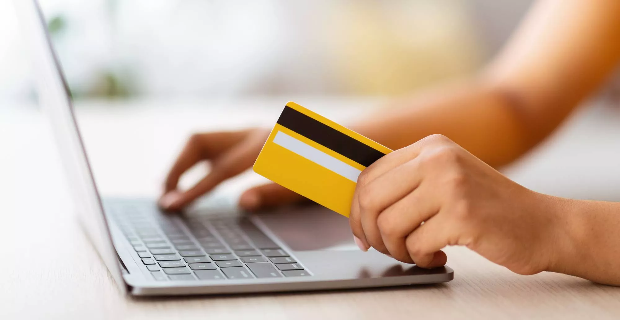 A shopper on her laptop and holding her credit card to start making Discover chargebacks
