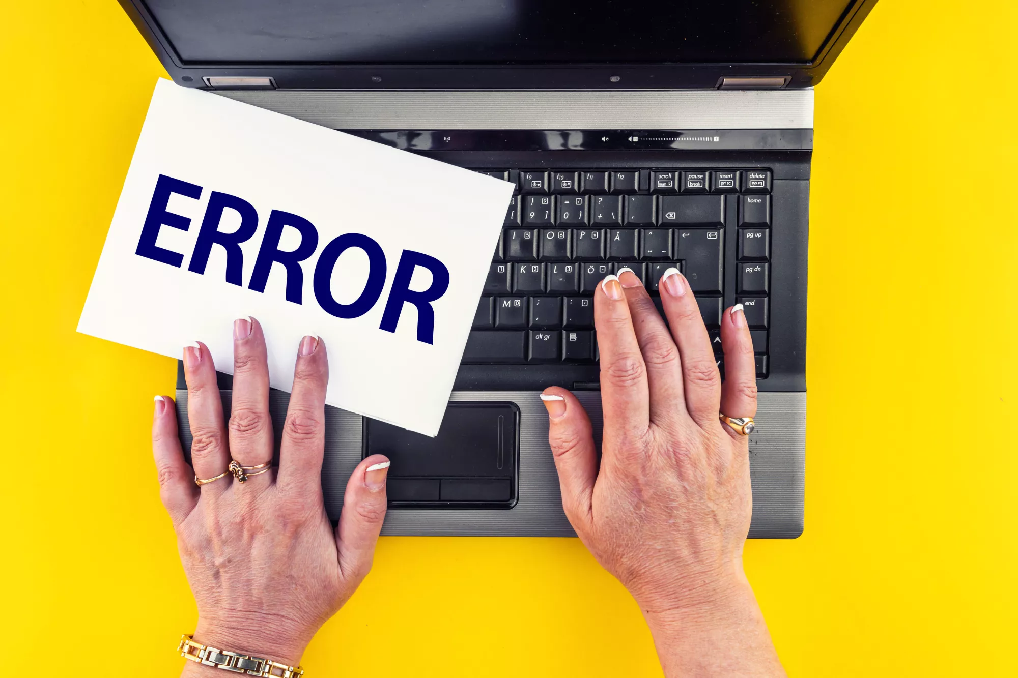 hands on the keyboard of an open laptop with a note saying "error" as someone receives ACH return code R62