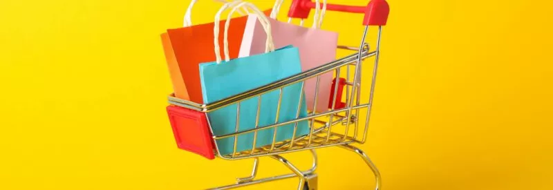 A small shopping cart with bags in it from a store that has good shopify pricing against a yellow background