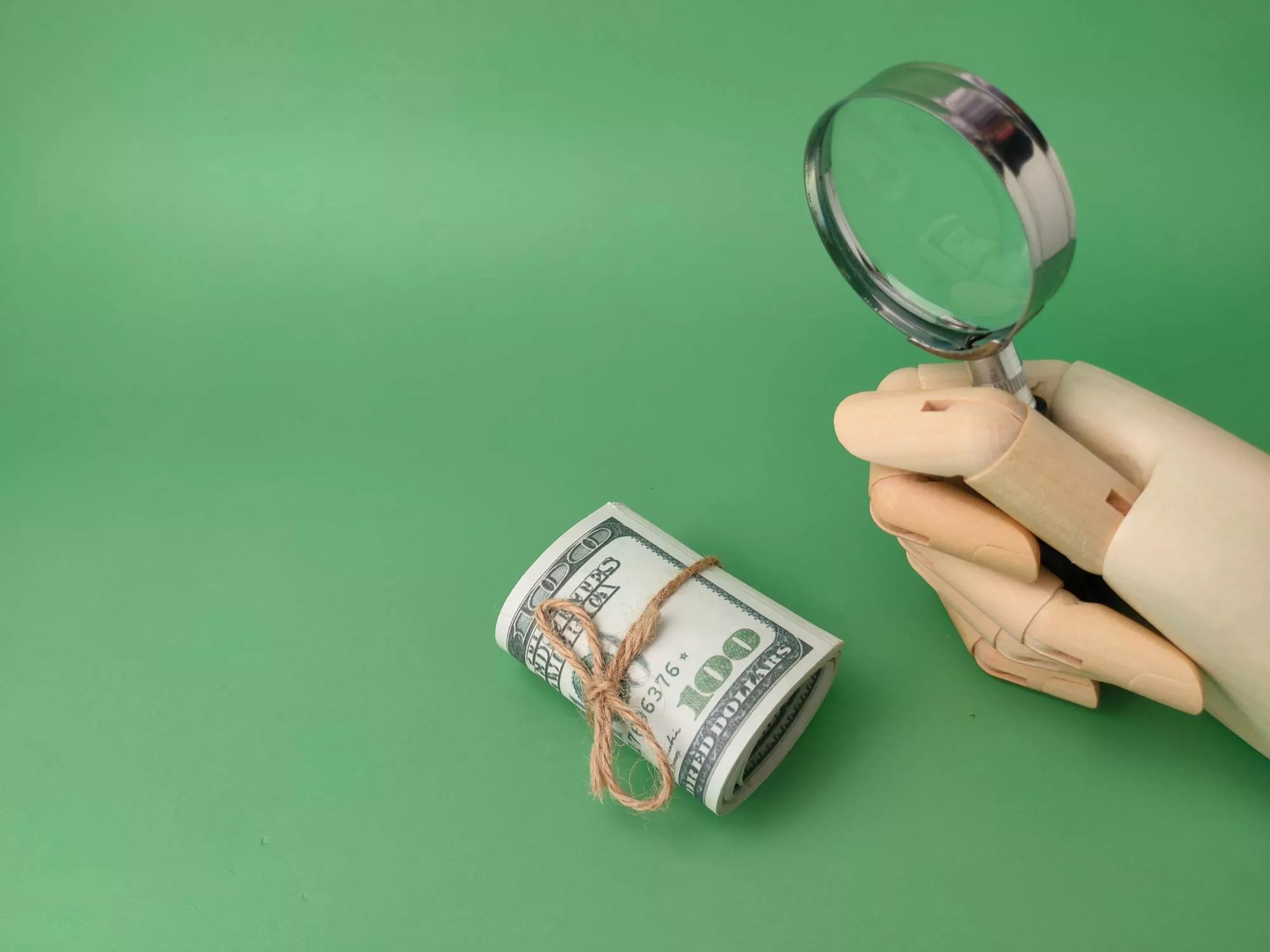An r63 return code appearing so a wooden hand uses magnifying glass to look at ACH transaction funds on green background