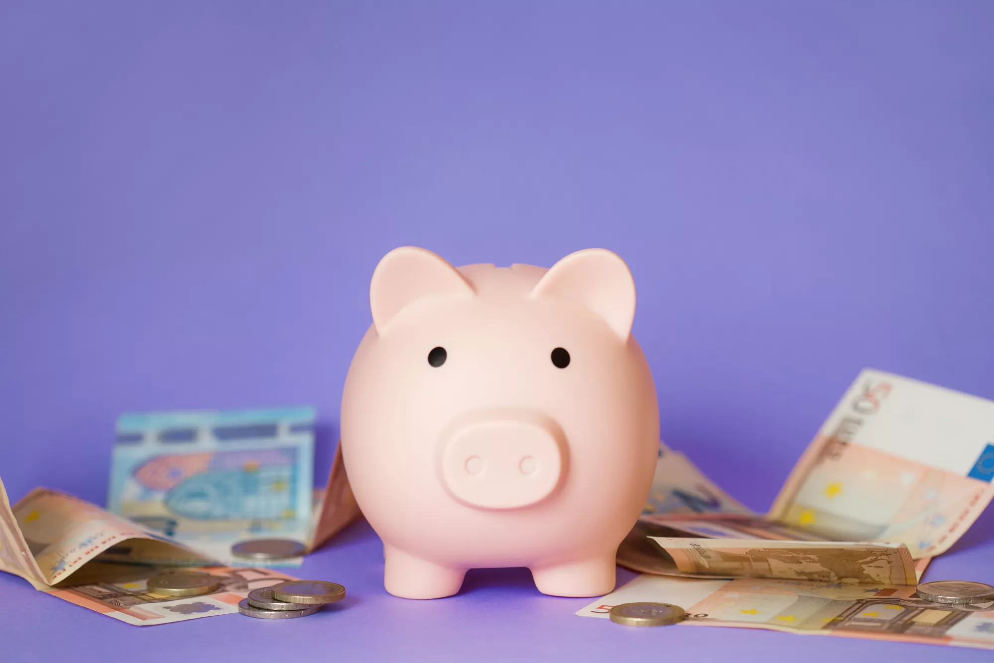 A piggy bank with money against a purple background to represent an upfront reserve as a savings account