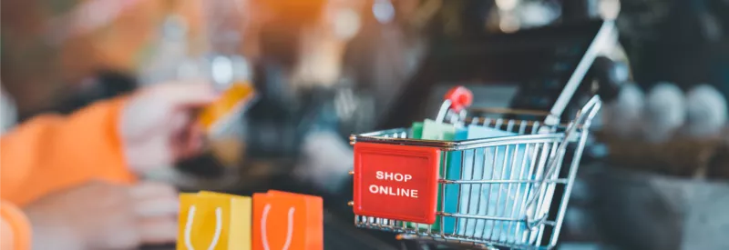 A shopping cart that says shop online on it with a computer in the background after getting a high-risk payment gateway for bigcommerce