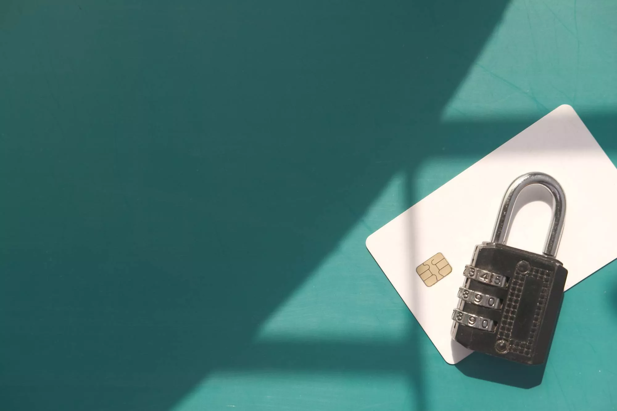 A lock and credit card tokens on a shadowy teal background