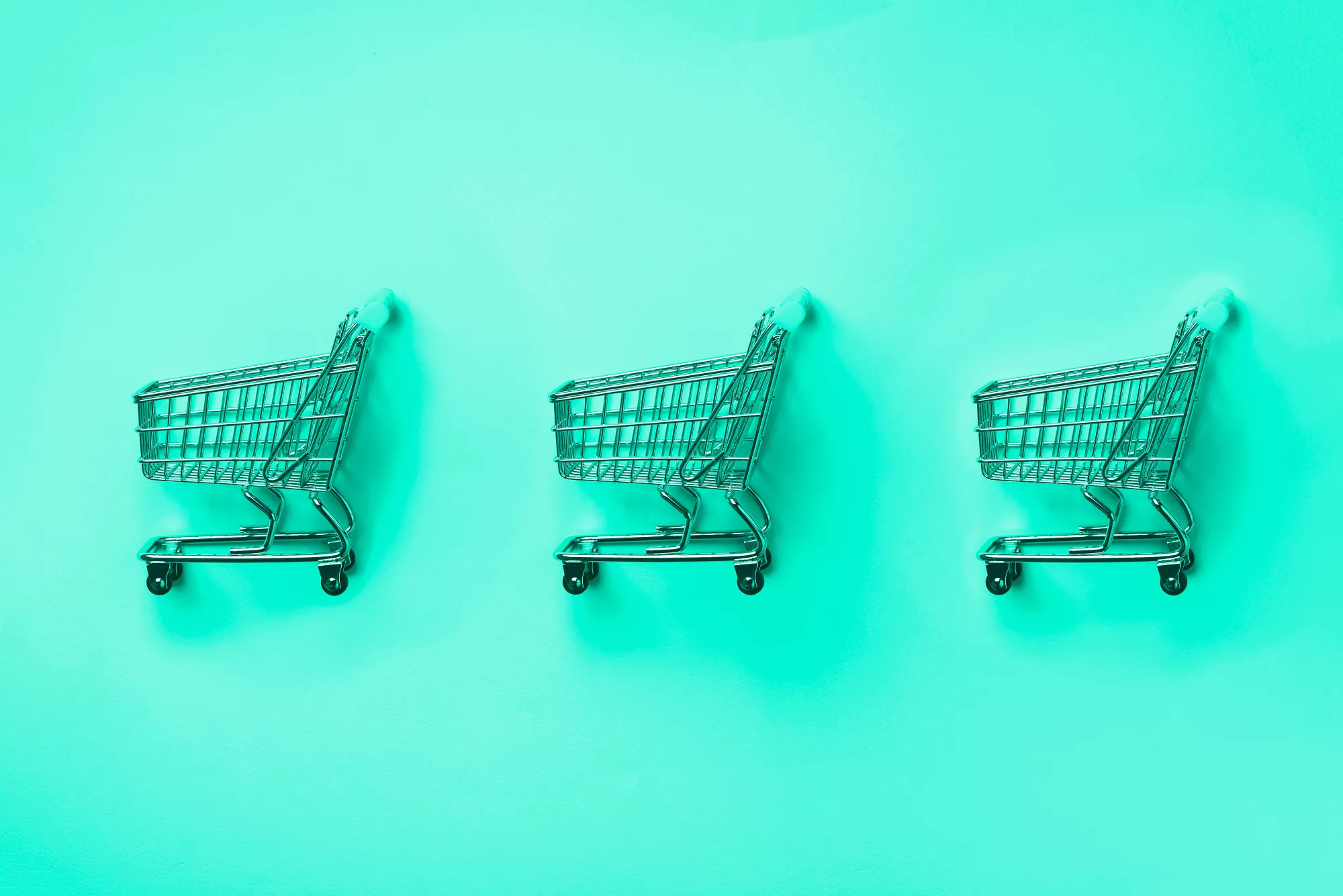 three shopping carts against a green background as a merchant debates merchant account vs stripe