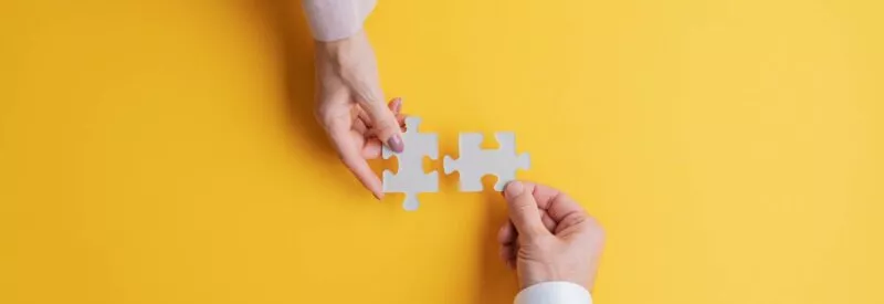 Business owners integrating payments as simply as using puzzle pieces on a yellow background.