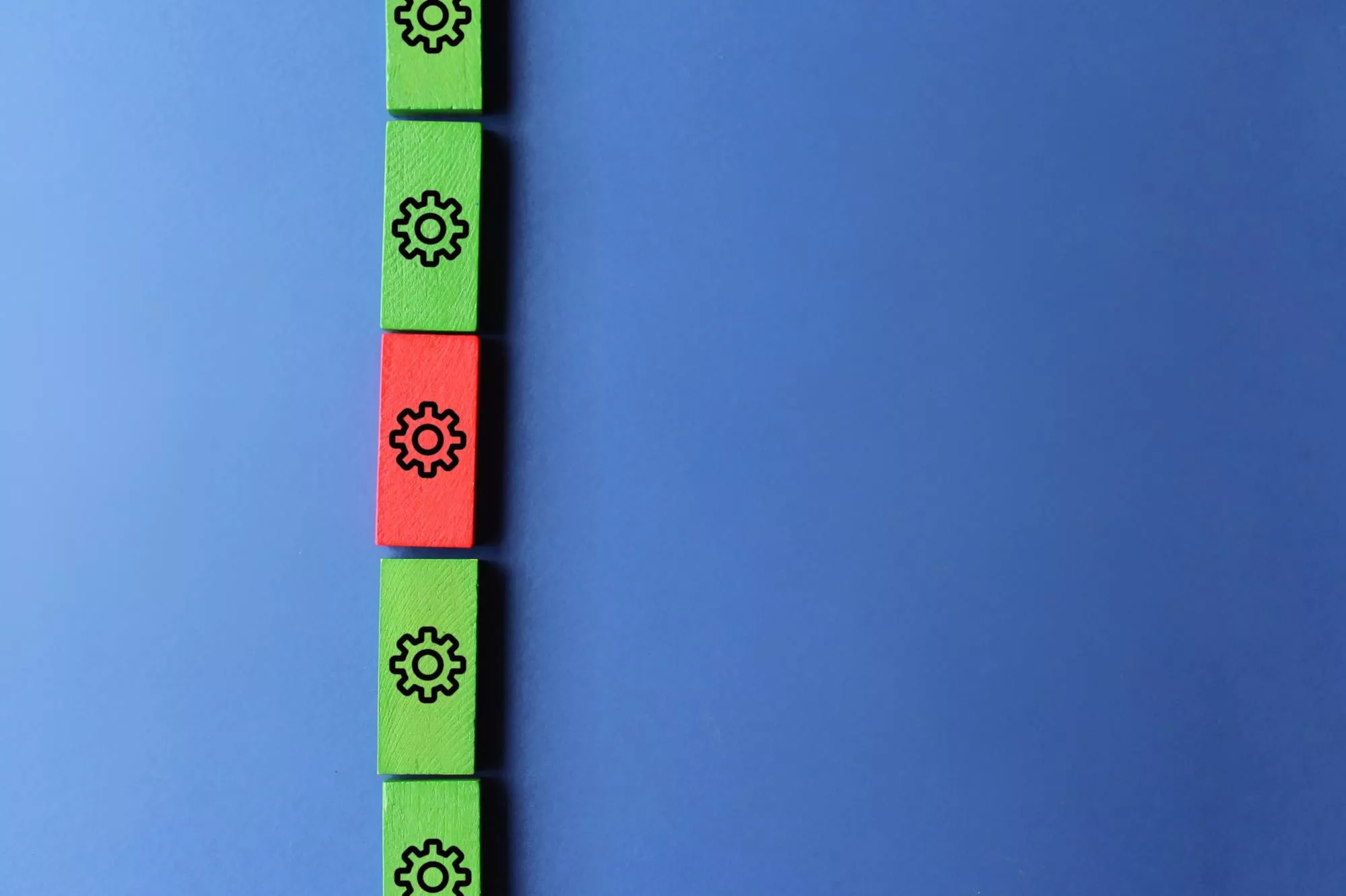 A red wooden block gear in the middle of green wooden block gears to represent ACH return code 80.