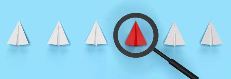 A sky blue background with a black magnifying glass focusing on a red paper airplane to find the error causing ACH return code 82.