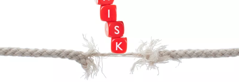 Two ropes balancing red blocks that spell out 'risk' to represent visa high-risk mcc codes.