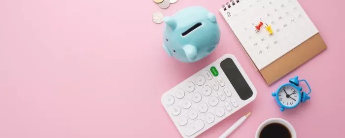 blue piggy bank and calculator on pink backdrop