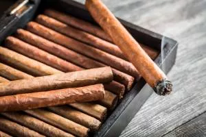 Cigar wooden box set with a burning cigar on top. 