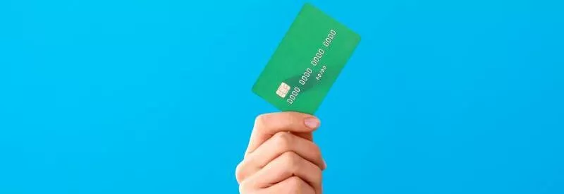 A hand holding a green credit card against a blue background after finding out is venmo safe for business