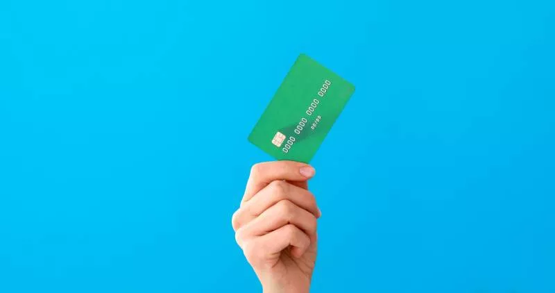 A hand holding a green credit card against a blue background after finding out is venmo safe for business