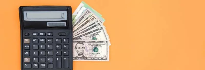 Cash and a calculator on an orange background ready for accepting payments through quickbooks.