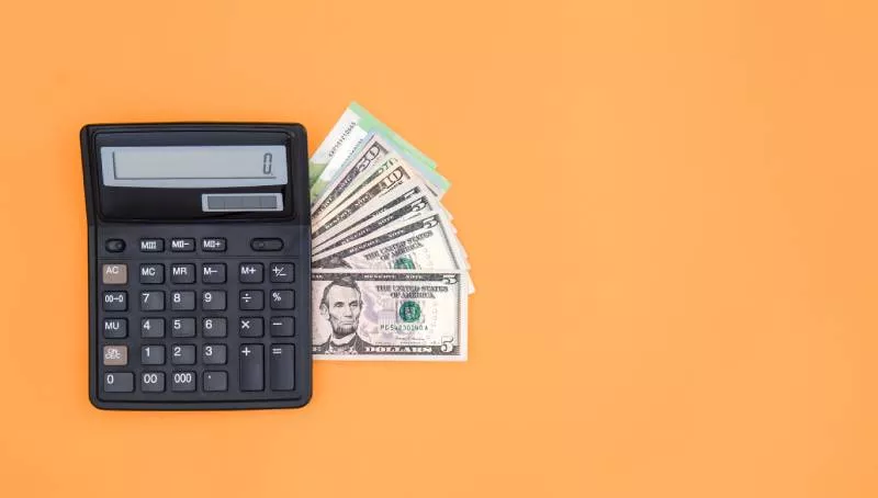 Cash and a calculator on an orange background ready for accepting payments through quickbooks.