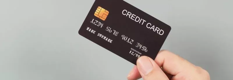 Someone holding a black card against a gray background to use on an NMI payment gateway.