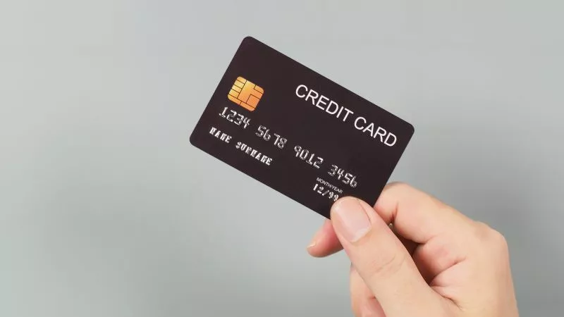 Someone holding a black card against a gray background to use on an NMI payment gateway.