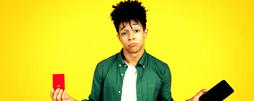 A frowning young man holding a phone and declined credit card