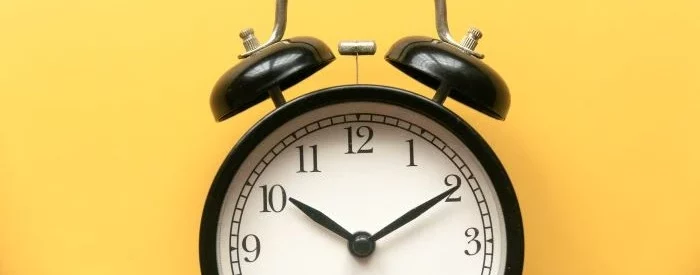 A timeclock in front of a yellow background to show how long does it take for an eCheck to clear.