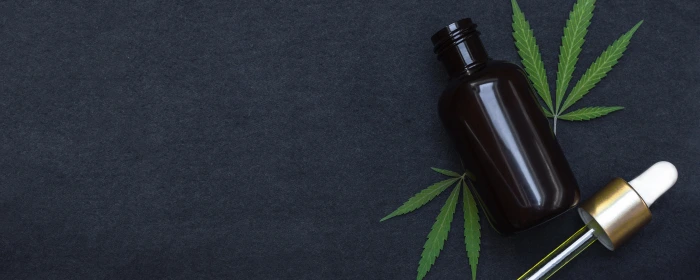 A CBD bottle laying on top of a CBD leaf obtained after learning how to get a CBD license.