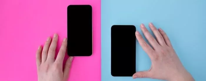 A person holding two phones against a pink and blue background
