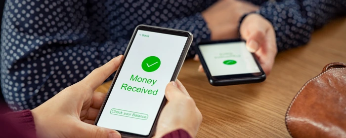 Two phones exchanging money at a business that set up Zelle for business.