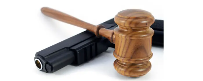 A gun and a gavel on a white table