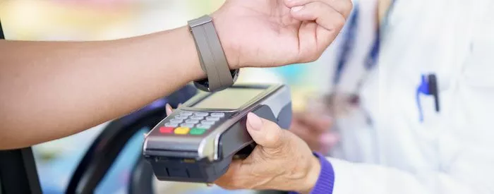A customer using their watch to pay at a terminal thanks to a payment facilitator