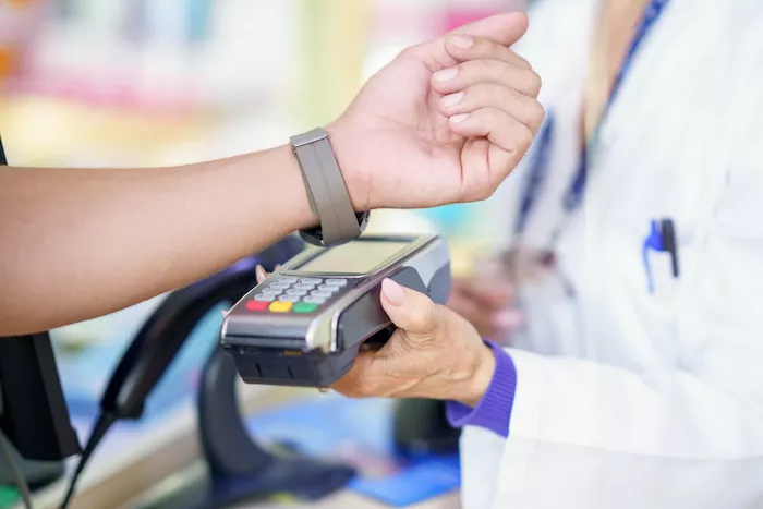 A customer using their watch to pay at a terminal thanks to a payment facilitator