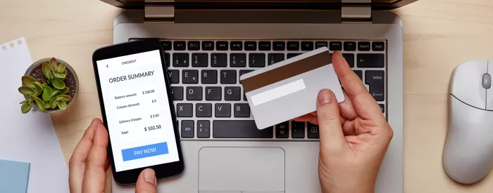 A person holding a credit card and a cell phone buying on a Shopify or Squarespace website.