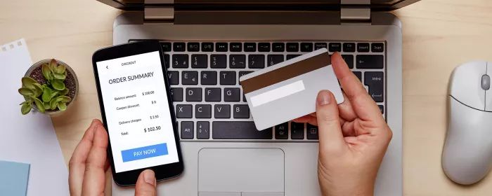 A person holding a credit card and a cell phone buying on a Shopify or Squarespace website.
