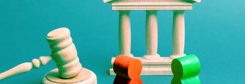 Wooden figures standing next to a bank and gavel.