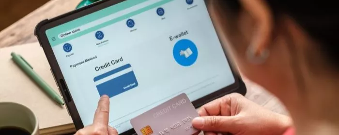 A close up on a woman using a credit card on a tablet.
