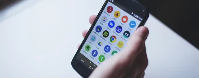 Man holding a phone with many apps on his screen.