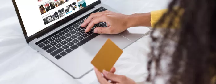 A woman goes on her laptop to purchase something using Big Cartel or Shopify.