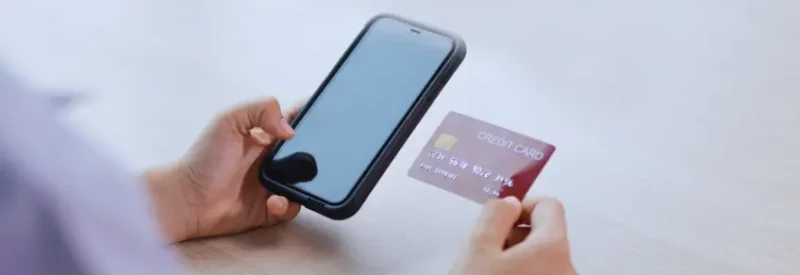 Hands are holding a credit card next to a cellphone, while a cash app payment is pending.