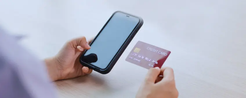 Hands are holding a credit card next to a cellphone, while a cash app payment is pending.