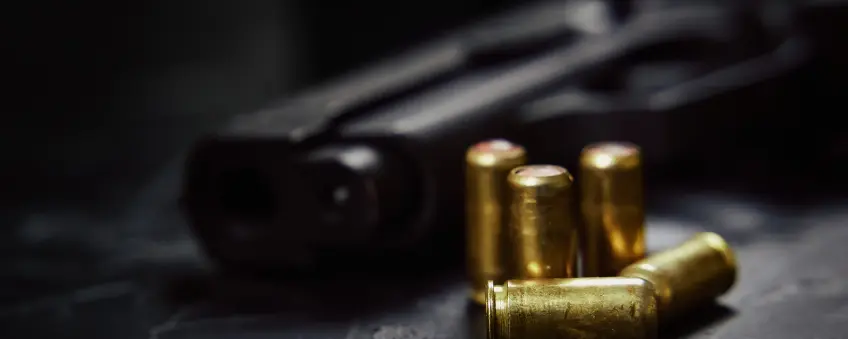 Barrel of a gun and bullets next to it, sold through an Alabama FFL.