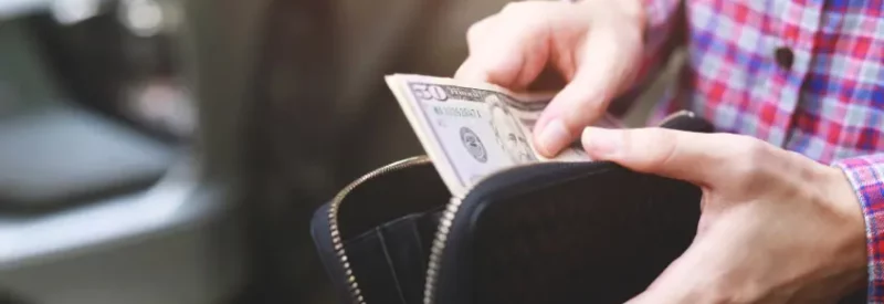 A man taking out cash from his wallet at a store that offers dual pricing.