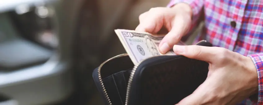 A man taking out cash from his wallet at a store that offers dual pricing.