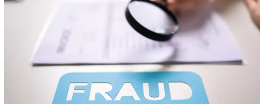 A magnifying glass looking over a pad with the word fraud, using fraud prevention strategies.