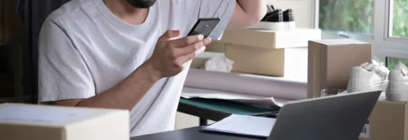 A business owner holding a credit card in front of a laptop, excited to choose a Stripe Connect Alternative.