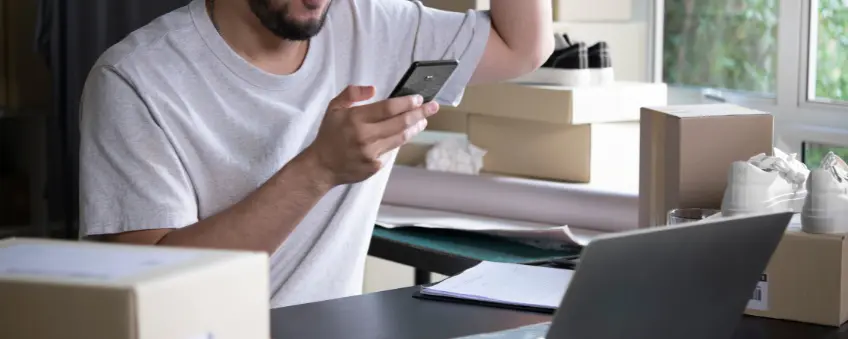 A business owner holding a credit card in front of a laptop, excited to choose a Stripe Connect Alternative.