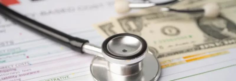 A stethoscope on top of healthcare documents and dollar bills as part of revenue cycle management.