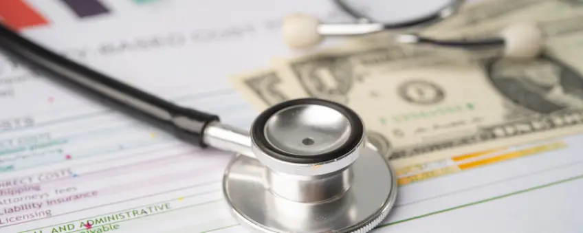 A stethoscope on top of healthcare documents and dollar bills as part of revenue cycle management.